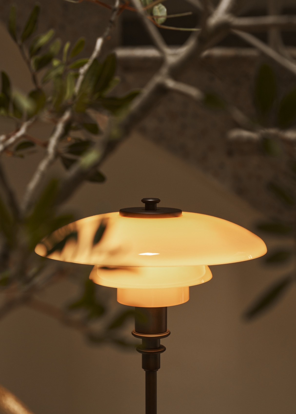 PH 2/1 Table Lamp Limited Edition 2024 casting warm light beside indoor greenery, © 2025 Louis Poulsen.